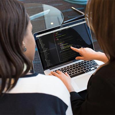 Photo of woman pointing at laptop screen with code