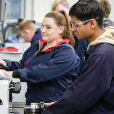 Young people working on machinery wearing safety goggles